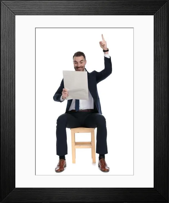Framed Print : Celebrating businessman holding newspaper and pointing upwards while sitting on a chair on white studio background Framed Print : Celebrating businessman holding newspaper and pointing upwards while sitting on a chair on white studio background