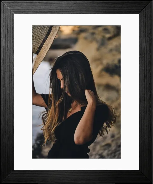 Framed Print : Young long haired smiling female model looking away holding hat in air on beach Framed Print : Young long haired smiling female model looking away holding hat in air on beach