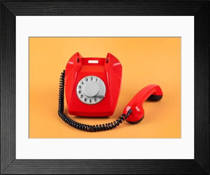 Framed Print : One red telephone with handset on pale orange background Framed Print : One red telephone with handset on pale orange background