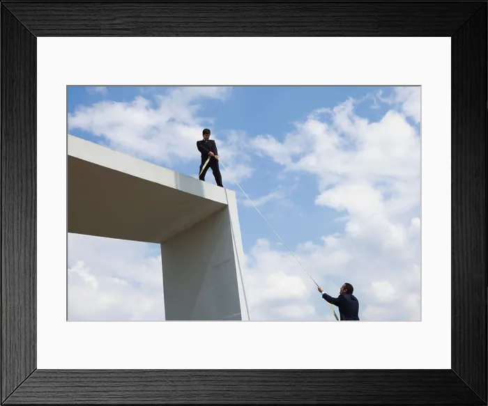 Framed Print : Businessman lends helping hand to colleague