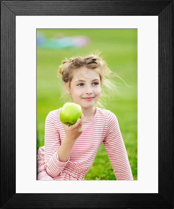 Framed Print : portrait of adorable smiling girl eating green apple while sitting on grass at park Framed Print : portrait of adorable smiling girl eating green apple while sitting on grass at park