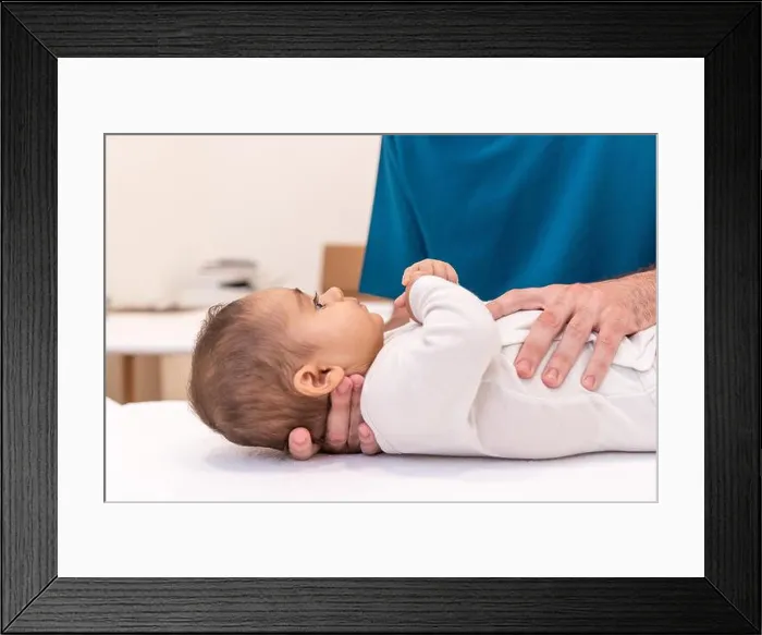 Framed Print : Close-up photo of an unrecognizable doctor examining baby in office