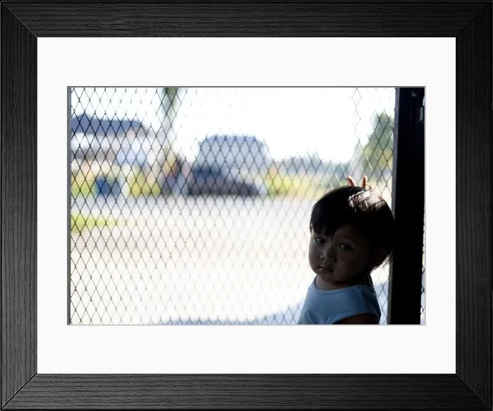 Framed Print : The boy is holding his hands on the fence Framed Print : The boy is holding his hands on the fence