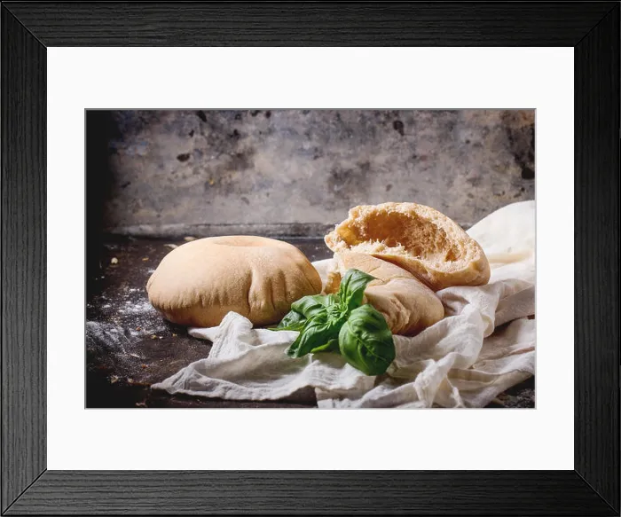 Framed Print : Two homemade whole and sliced pita bread stuffed with fresh basil on white textile, served with flour over dark table Framed Print : Two homemade whole and sliced pita bread stuffed with fresh basil on white textile, served with flour over dark table