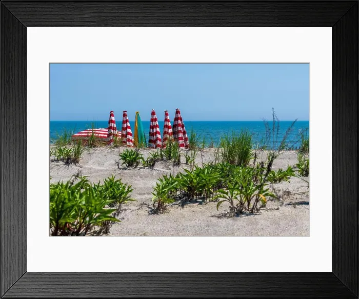 Framed Print : looking over the beach dune at the water and red and white stripe umbrellas for rent Framed Print : looking over the beach dune at the water and red and white stripe umbrellas for rent