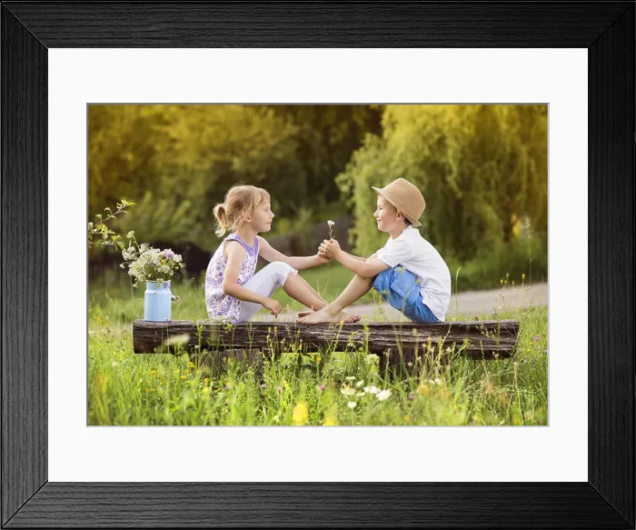 Framed Print : Cute boy and girl in love. They sitting on bench at sunset Framed Print : Cute boy and girl in love. They sitting on bench at sunset