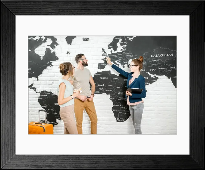 Framed Print : Young couple of travelers choosing a summer trip with travel agent pointing on Great Britain on the world map Framed Print : Young couple of travelers choosing a summer trip with travel agent pointing on Great Britain on the world map