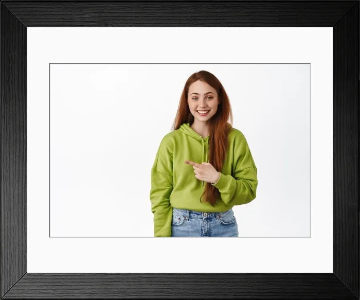 Framed Print : Image of cheerful redhead girl pointing finger left and smiles white teeth Framed Print : Image of cheerful redhead girl pointing finger left and smiles white teeth