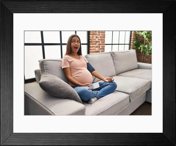 Framed Print : Young pregnant woman using blood pressure monitor sitting on the sofa angry and mad screaming frustrated and furious Framed Print : Young pregnant woman using blood pressure monitor sitting on the sofa angry and mad screaming frustrated and furious