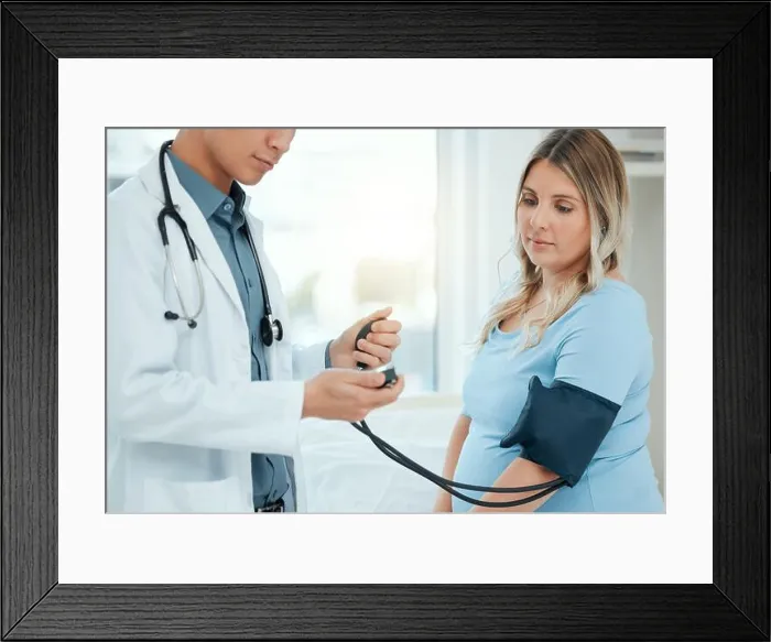 Framed Print : a doctor using a blood pressure gauge during a checkup with his pregnant patient