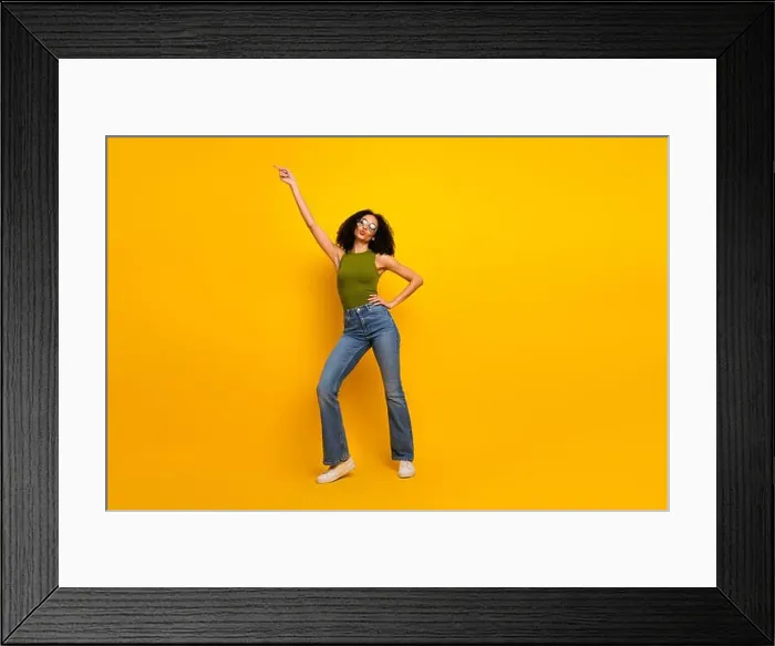 Framed Print : Joyful young woman in trendy outfit posing against bright yellow background with confident energy Framed Print : Joyful young woman in trendy outfit posing against bright yellow background with confident energy