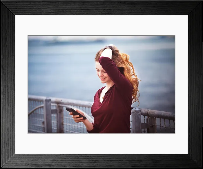 Framed Print : Woman with hand in hair using smart phone against river Framed Print : Woman with hand in hair using smart phone against river
