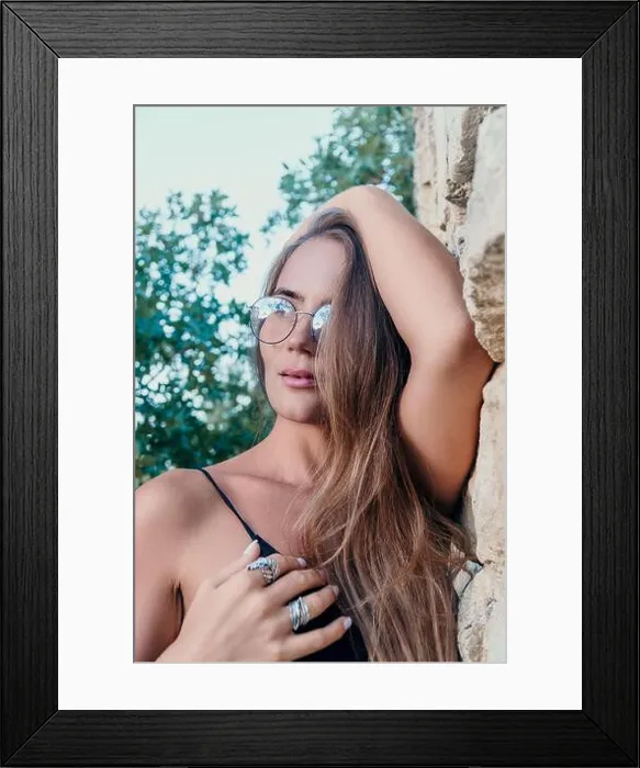 Framed Print : Woman Glasses Wall - A woman wearing glasses leans against a stone wall in a natural outdoor setting Framed Print : Woman Glasses Wall - A woman wearing glasses leans against a stone wall in a natural outdoor setting