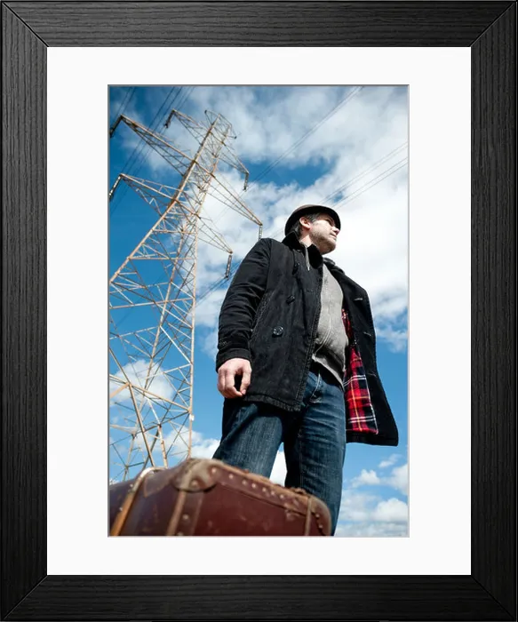 Framed Print : Man with suitcase in a field under power lines Framed Print : Man with suitcase in a field under power lines