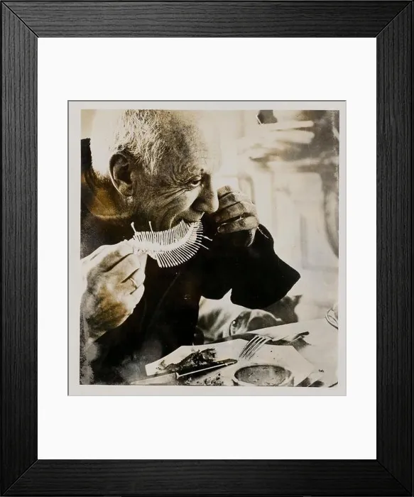 Framed Print : Pablo Picasso eats a fish whose bones are then printed in clay Framed Print : Pablo Picasso eats a fish whose bones are then printed in clay