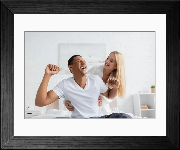 Framed Print : cheerful woman tickling african american boyfriend laughing in bedroom Framed Print : cheerful woman tickling african american boyfriend laughing in bedroom