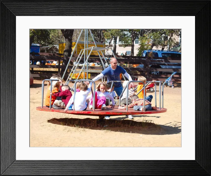 Framed Print : Father pushing kids on a merry-go-round at a playground Framed Print : Father pushing kids on a merry-go-round at a playground