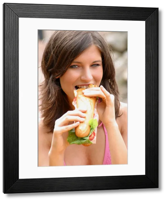 Framed Print : Portrait of a young woman eating hotdog Framed Print : Portrait of a young woman eating hotdog