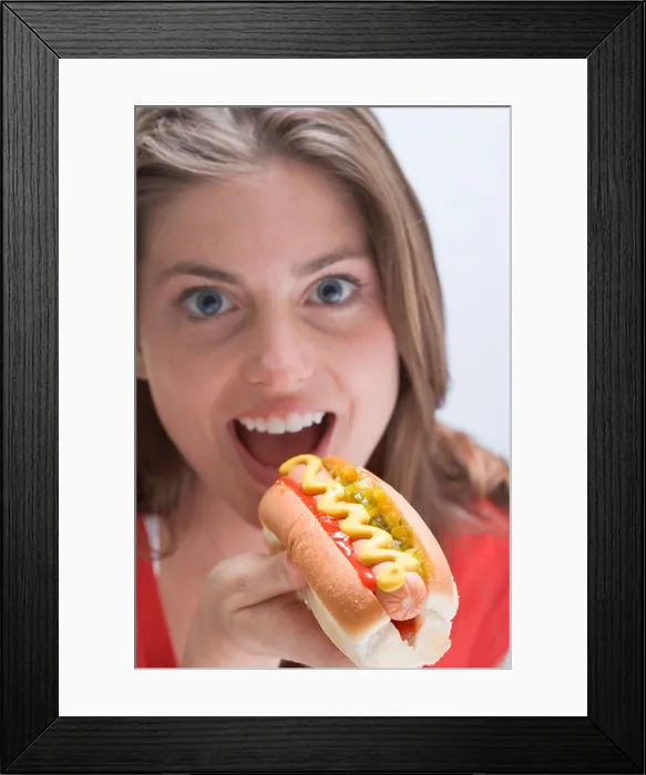 Framed Print : Woman eating a hot dog with mustard - Framed Print : Woman eating a hot dog with mustard -