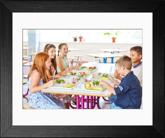 Framed Print : Happy kids having meal with cutlery while sitting together at table in school canteen Framed Print : Happy kids having meal with cutlery while sitting together at table in school canteen