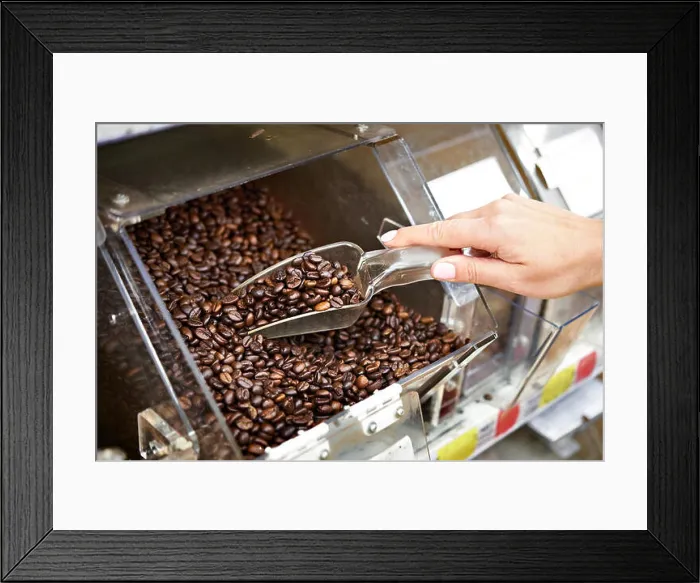 Framed Print : Buyer in shop buys coffee using scoop for the products Framed Print : Buyer in shop buys coffee using scoop for the products