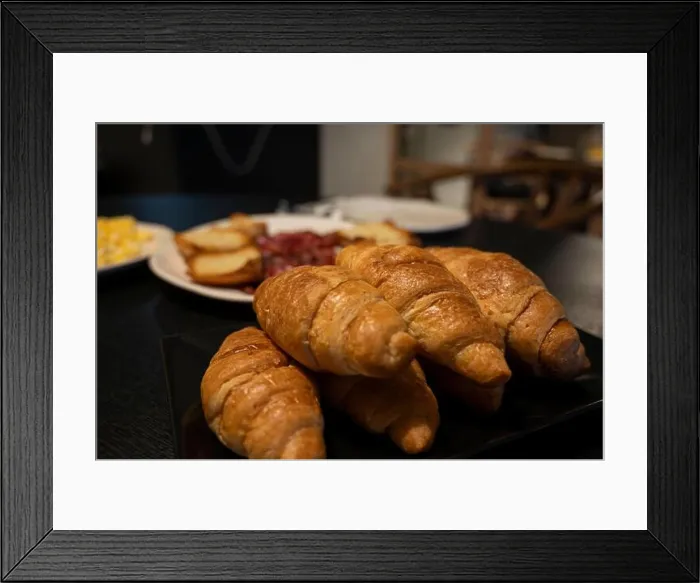 Framed Print : A plate of croissants sits on a table next to a plate of potatoes Framed Print : A plate of croissants sits on a table next to a plate of potatoes