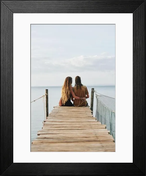 Framed Print : Couple in love sitting on wooden pier and enjoying beautiful seascape, view from the back Framed Print : Couple in love sitting on wooden pier and enjoying beautiful seascape, view from the back