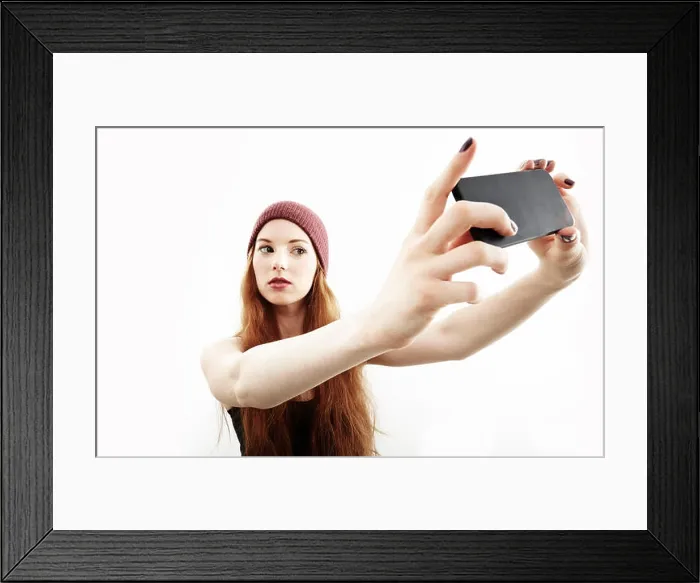 Framed Print : Studio portrait of young woman making selfie on smartphone Framed Print : Studio portrait of young woman making selfie on smartphone