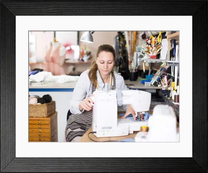 Framed Print : Young woman sewer working with modern sewing machine Framed Print : Young woman sewer working with modern sewing machine