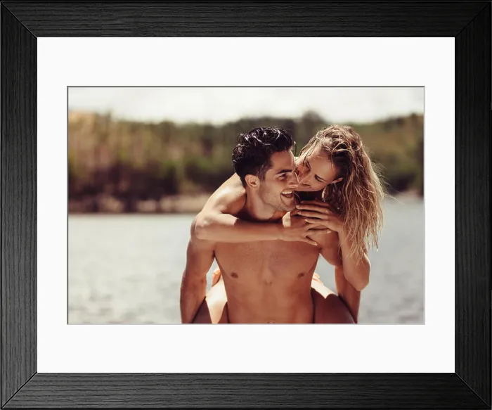 Framed Print : Portrait of romantic young man piggybacking his girlfriend. Young couple having fun at the lakeside