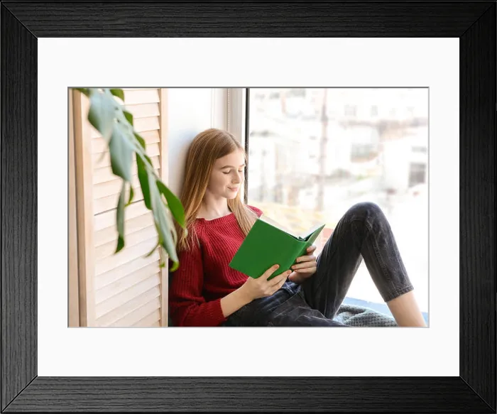 Framed Print : Cute teenage girl reading book on window sill at home Framed Print : Cute teenage girl reading book on window sill at home