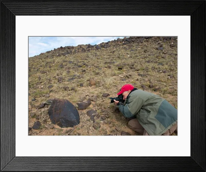 Framed Print : A tourist is photographing petroglyphs at the Black Mountains in the Gobi Desert near Bulgan in southern Mongolia Framed Print : A tourist is photographing petroglyphs at the Black Mountains in the Gobi Desert near Bulgan in southern Mongolia