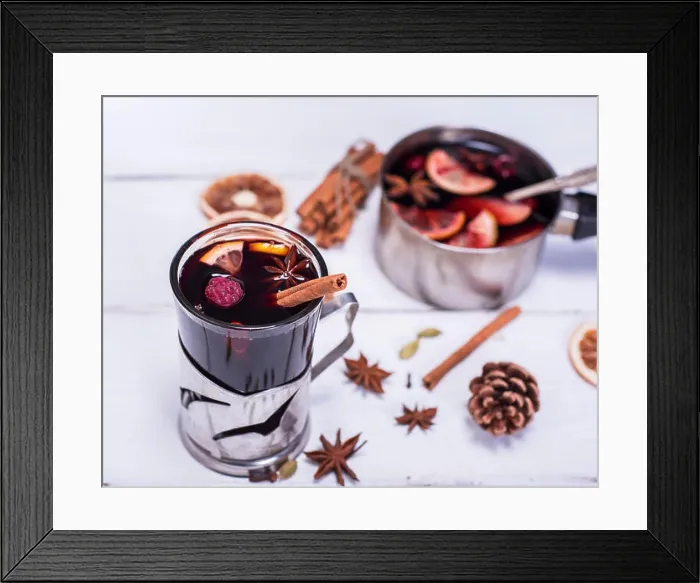 Framed Print : mulled wine in a glass with an iron cup holder on a white wooden background, top view Framed Print : mulled wine in a glass with an iron cup holder on a white wooden background, top view