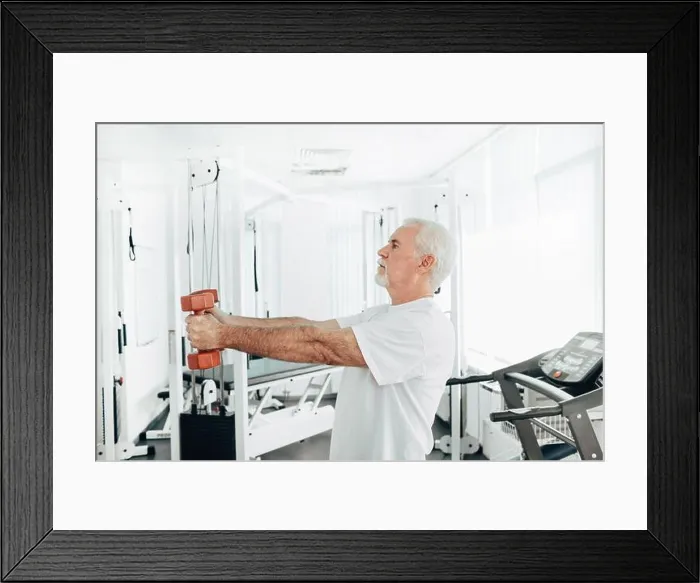 Framed Print : Senior man lifting weights at an exercise class. healthy lifestyle old people