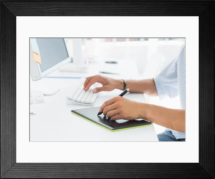 Framed Print : Close-up side view of an artist drawing something on graphic tablet with pen Framed Print : Close-up side view of an artist drawing something on graphic tablet with pen