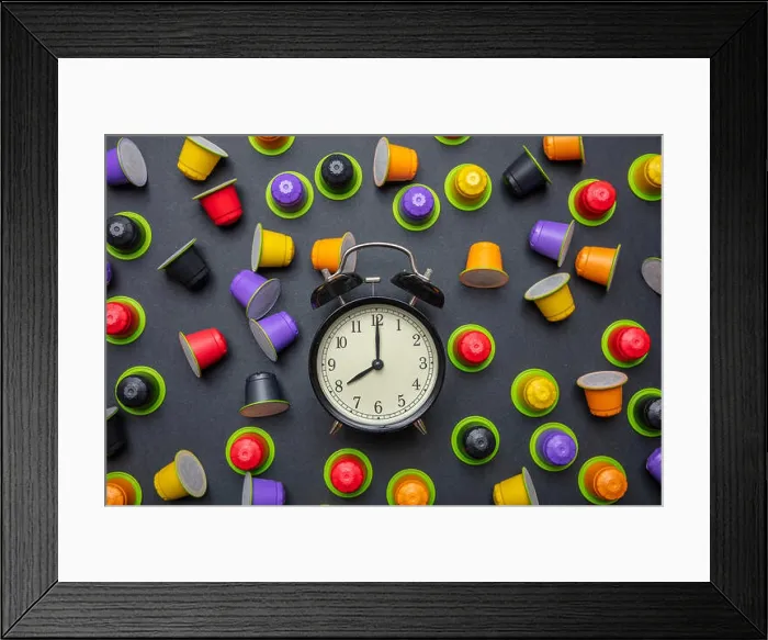 Framed Print : Coffee time. Alarm clock and espresso capsules, pods eco friendly, compostable on black color background, top view Framed Print : Coffee time. Alarm clock and espresso capsules, pods eco friendly, compostable on black color background, top view