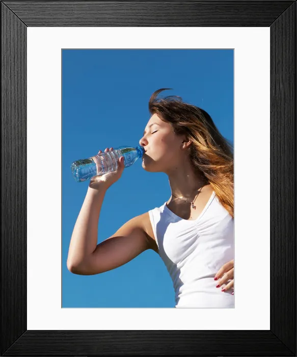 Framed Print : The girl drinking water from a bottle against the sky Framed Print : The girl drinking water from a bottle against the sky