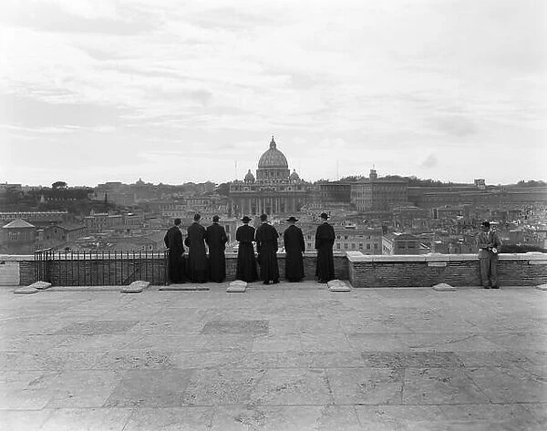 1950s ROME ITALY BACK VIEW OF STUDENT PRIESTS LINED UP BY WALL OVERLOOKING CITY WITH VIEW OF ST. PETERS BASILICA IN BACKGROUND