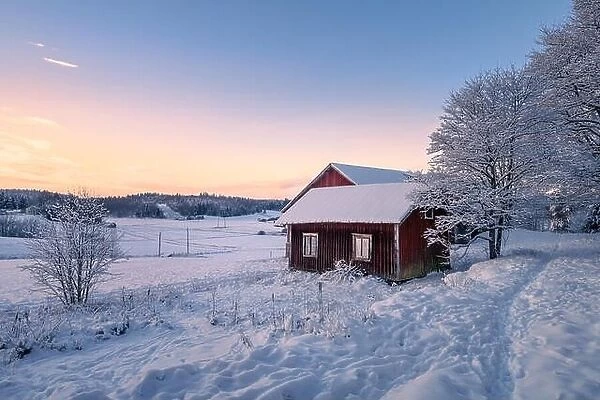 Abandoned house with snowy landscape and sunset at winter evening in Finland