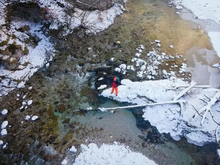 Framed Print : Aerial drone shot of hiker with backpack, orange cap and orange pants next to cold mountain stream in canyon Framed Print : Aerial drone shot of hiker with backpack, orange cap and orange pants next to cold mountain stream in canyon