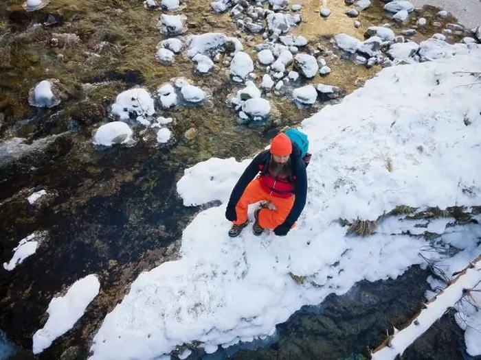 Framed Print : Aerial drone shot of hiker with backpack, orange cap and orange pants next to cold mountain stream in canyon Framed Print : Aerial drone shot of hiker with backpack, orange cap and orange pants next to cold mountain stream in canyon