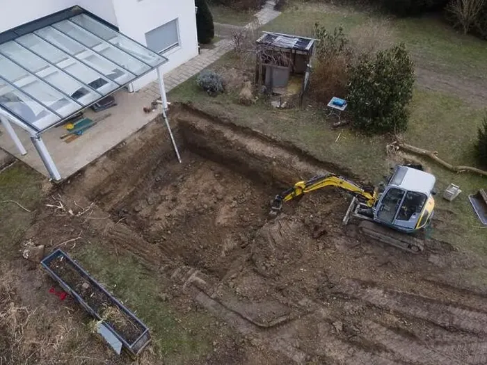 Framed Print : aerial drone shot of small, yellow excavator stands in a large garden and digs a hole for a pool in austria Framed Print : aerial drone shot of small, yellow excavator stands in a large garden and digs a hole for a pool in austria