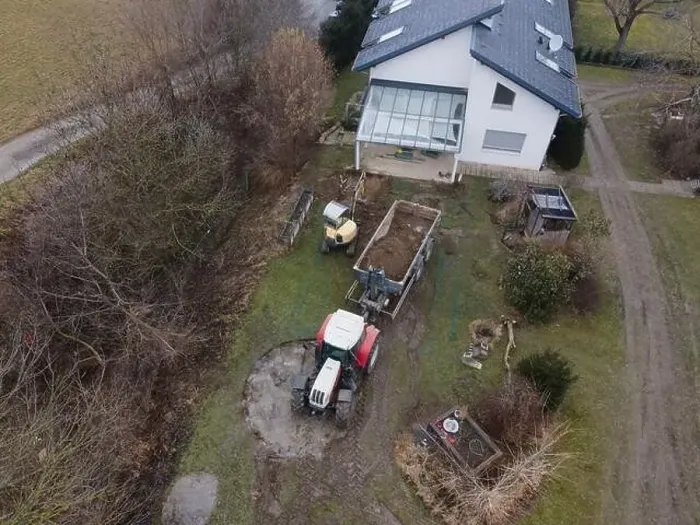 Framed Print : aerial drone shot of small, yellow excavator stands in a large garden and digs a hole for a pool in austria Framed Print : aerial drone shot of small, yellow excavator stands in a large garden and digs a hole for a pool in austria