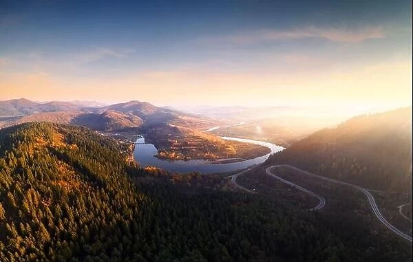 Aerial drone view over the autumn mountains with mountain road serpentine, river and forest. Landscape photography