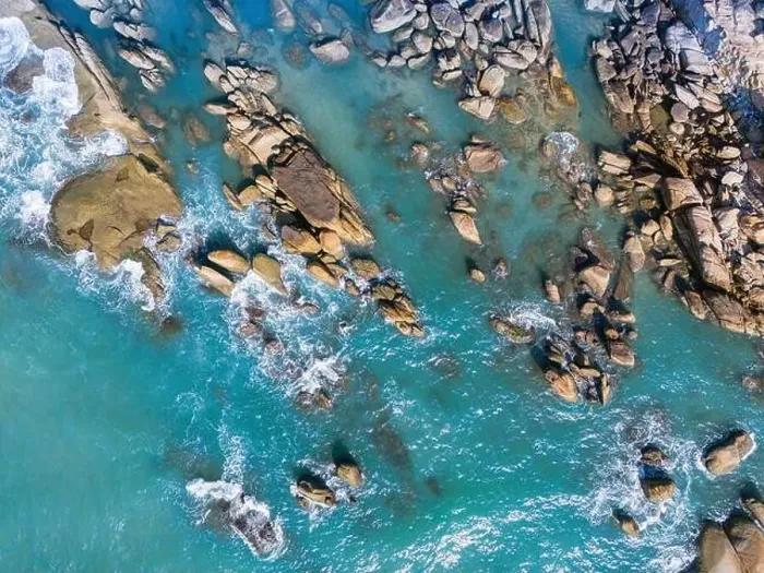 Framed Print : Aerial drone top view of beautiful waves crashing on the rocky island coast Framed Print : Aerial drone top view of beautiful waves crashing on the rocky island coast