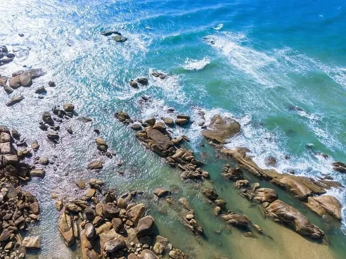 Framed Print : Aerial drone top view of beautiful waves crashing on the rocky island coast Framed Print : Aerial drone top view of beautiful waves crashing on the rocky island coast
