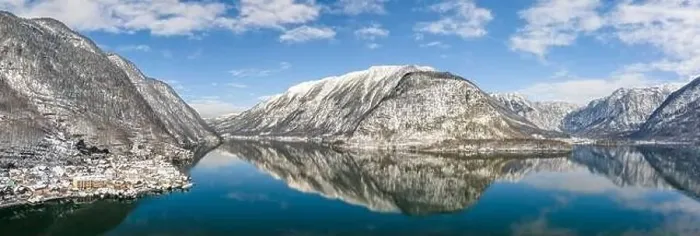 Framed Print : Aerial panoramic drone shot of snow mountains by Halstatt lake and village in snow under blue cear sky during winter Framed Print : Aerial panoramic drone shot of snow mountains by Halstatt lake and village in snow under blue cear sky during winter