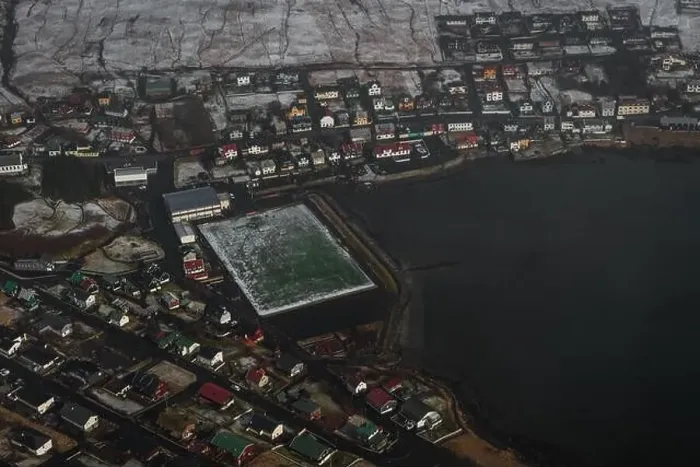 Framed Print : Aerial shot of the Faroese village Sandavagur as seen from a helicopter flight over snow-covered landscape in early Framed Print : Aerial shot of the Faroese village Sandavagur as seen from a helicopter flight over snow-covered landscape in early