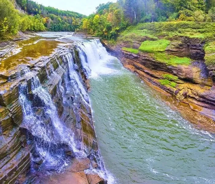 Framed Print : Aerial along stunning waterfall pouring over cliffs with lush forests in background Framed Print : Aerial along stunning waterfall pouring over cliffs with lush forests in background
