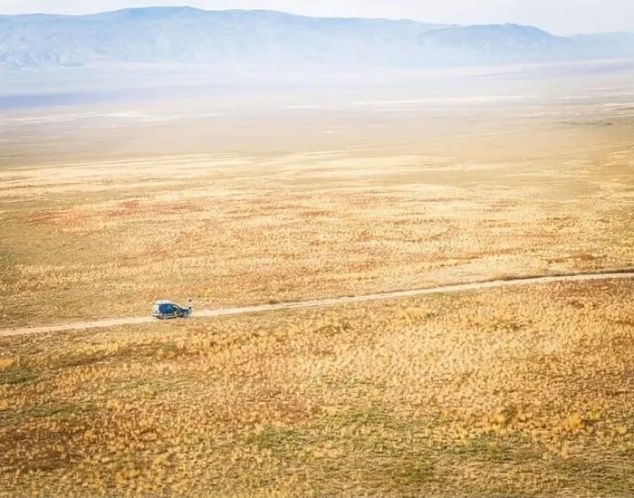 Framed Print : Aerial view of 4WD automobile driving across deserted vast landscape and mountains background VAshlovani national park Framed Print : Aerial view of 4WD automobile driving across deserted vast landscape and mountains background VAshlovani national park